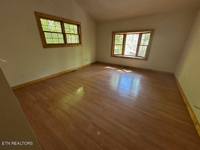 spare room with lofted ceiling and light hardwood / wood-style flooring