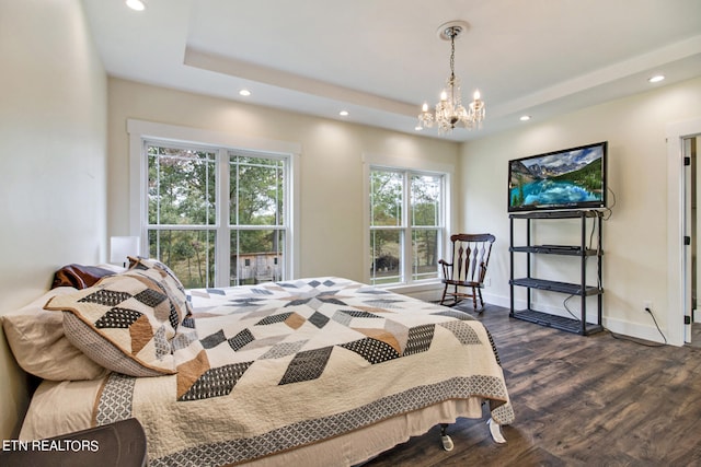 bedroom featuring a tray ceiling, dark wood-type flooring, and a chandelier