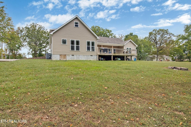 rear view of property featuring central AC unit, a deck, and a yard