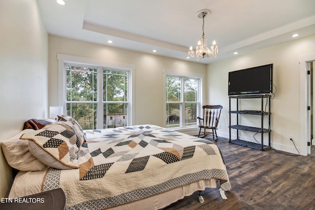 bedroom featuring an inviting chandelier, a tray ceiling, and dark hardwood / wood-style flooring