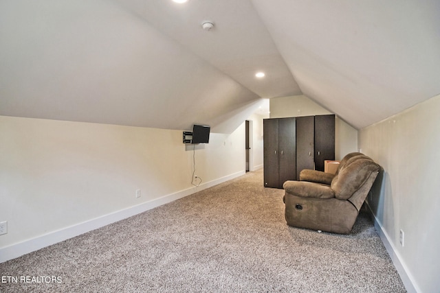 sitting room with vaulted ceiling and light carpet