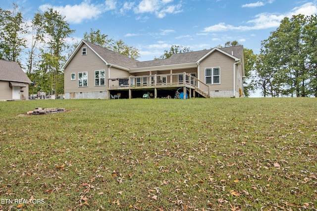 rear view of property featuring a wooden deck and a lawn