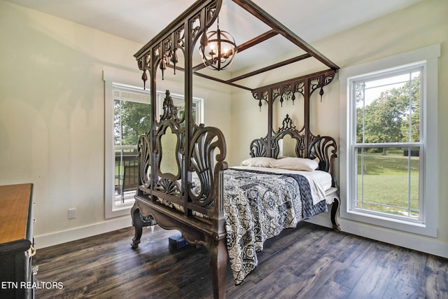 bedroom featuring an inviting chandelier and dark hardwood / wood-style flooring