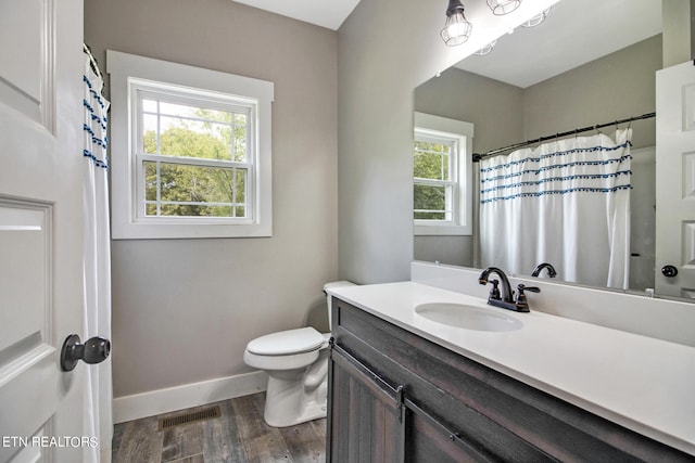 bathroom featuring hardwood / wood-style flooring, plenty of natural light, vanity, and toilet