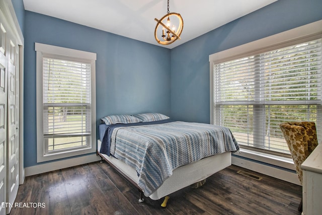 bedroom with a notable chandelier, dark hardwood / wood-style flooring, and multiple windows