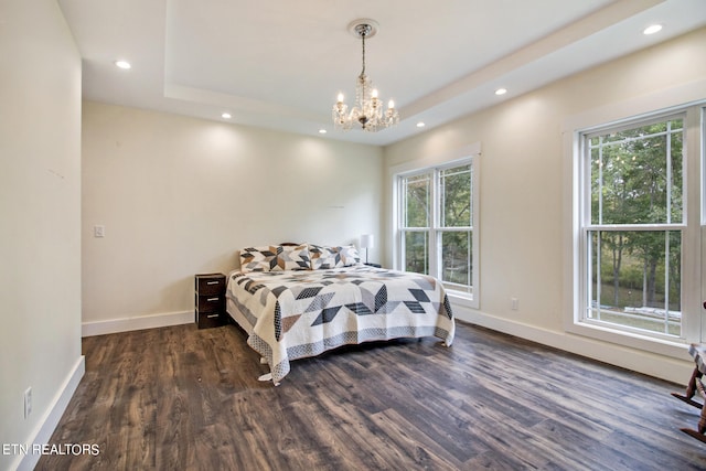 bedroom featuring a raised ceiling, an inviting chandelier, and dark wood-type flooring