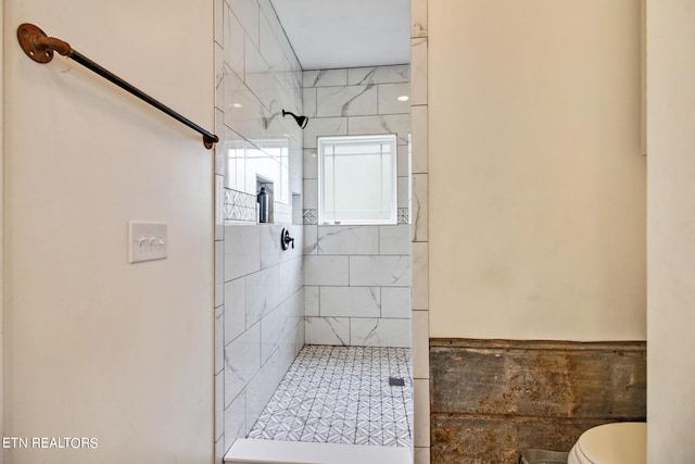 bathroom featuring tile walls, toilet, and tiled shower