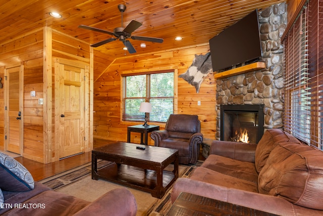 living room with wooden ceiling, hardwood / wood-style flooring, a stone fireplace, and wooden walls