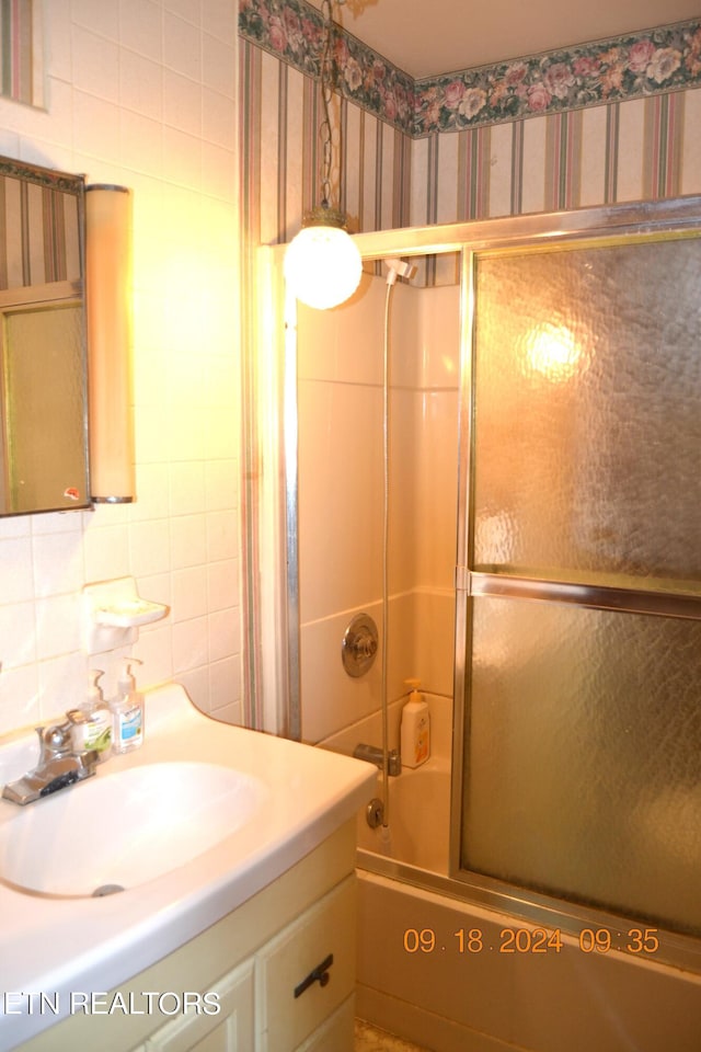 bathroom featuring tile walls, enclosed tub / shower combo, and sink