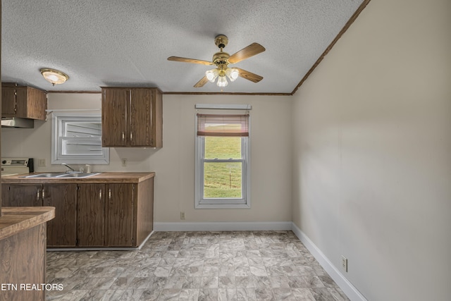 kitchen featuring a textured ceiling, ceiling fan, exhaust hood, and sink