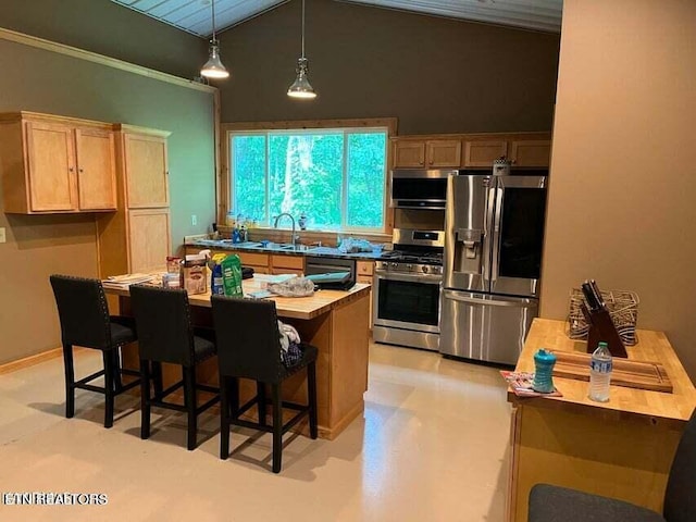 kitchen with sink, a kitchen island, decorative light fixtures, appliances with stainless steel finishes, and vaulted ceiling