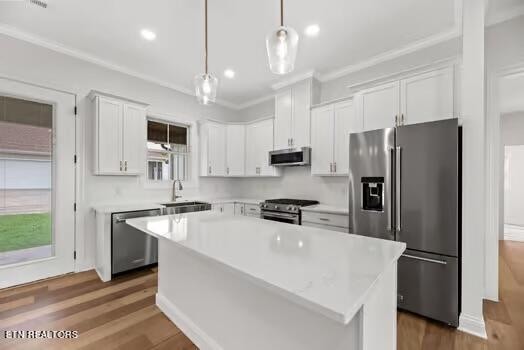 kitchen with sink, a kitchen island, white cabinets, and appliances with stainless steel finishes