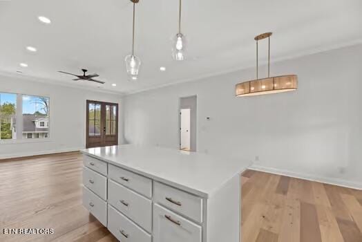 kitchen featuring decorative light fixtures, a kitchen island, white cabinetry, and ceiling fan