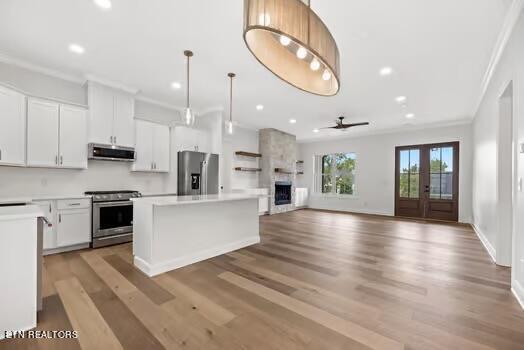 kitchen with white cabinets, ceiling fan, a kitchen island, and stainless steel appliances