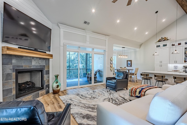 living room featuring wood-type flooring, a fireplace, ceiling fan, and high vaulted ceiling