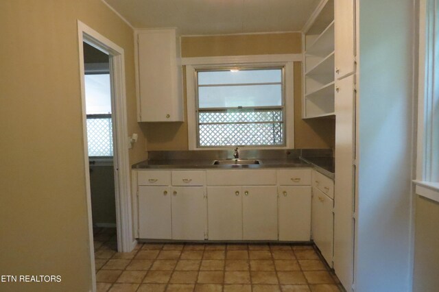 kitchen featuring light tile patterned flooring, white cabinetry, sink, and a wealth of natural light