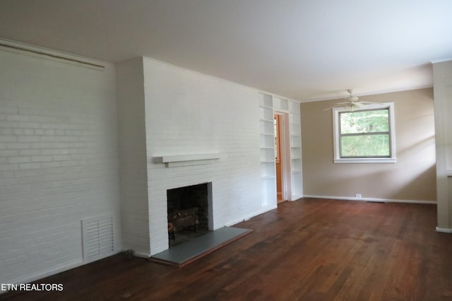 unfurnished living room with a large fireplace, ceiling fan, and dark wood-type flooring