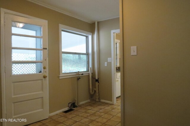 doorway to outside featuring plenty of natural light, light tile patterned floors, and crown molding