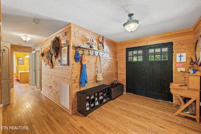 entrance foyer featuring wood walls, a textured ceiling, and hardwood / wood-style flooring