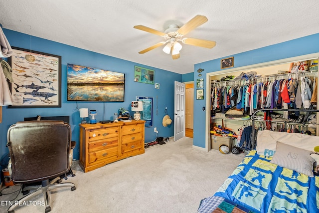 interior space with a textured ceiling, ceiling fan, light colored carpet, and a closet