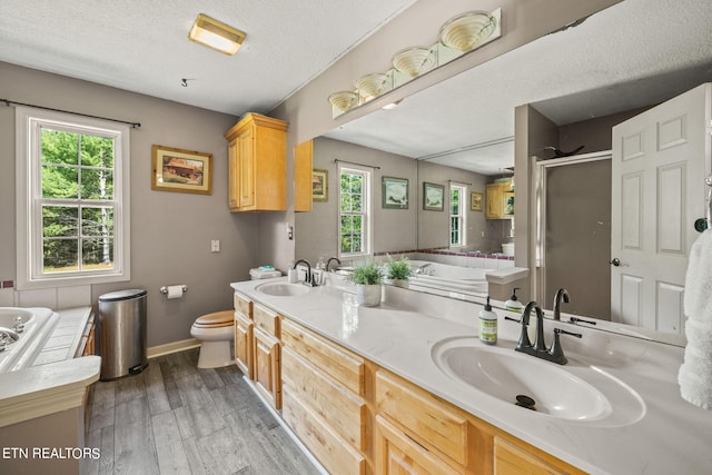 full bathroom featuring vanity, a textured ceiling, plus walk in shower, hardwood / wood-style flooring, and toilet