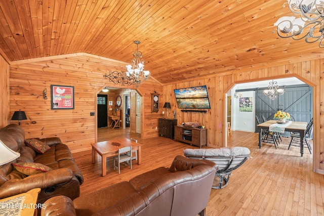 living room with vaulted ceiling, wooden walls, wooden ceiling, a notable chandelier, and light hardwood / wood-style floors