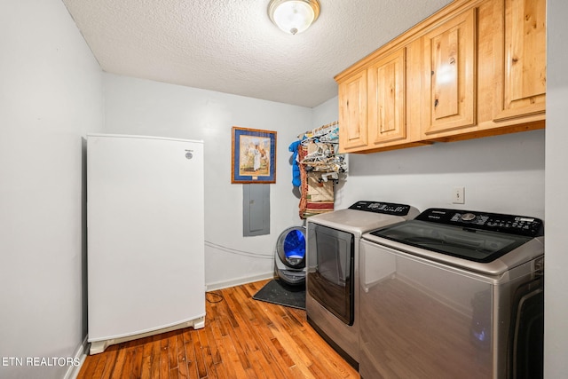 washroom with a textured ceiling, separate washer and dryer, light hardwood / wood-style flooring, and cabinets