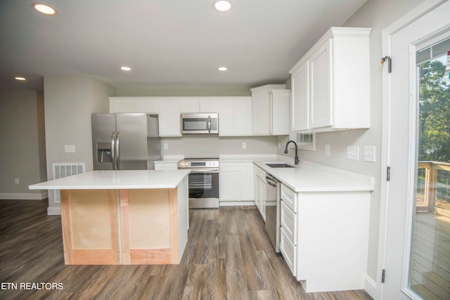 kitchen featuring white cabinets, sink, a kitchen island, wood-type flooring, and stainless steel appliances