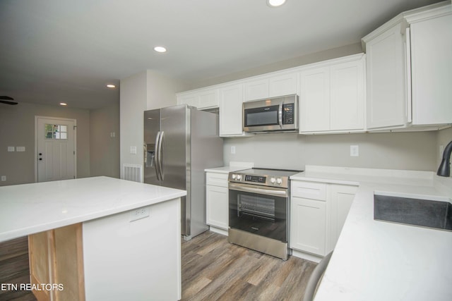 kitchen featuring a kitchen island, stainless steel appliances, dark wood-type flooring, and white cabinetry