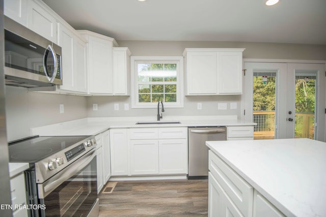 kitchen featuring appliances with stainless steel finishes, hardwood / wood-style floors, sink, and a wealth of natural light