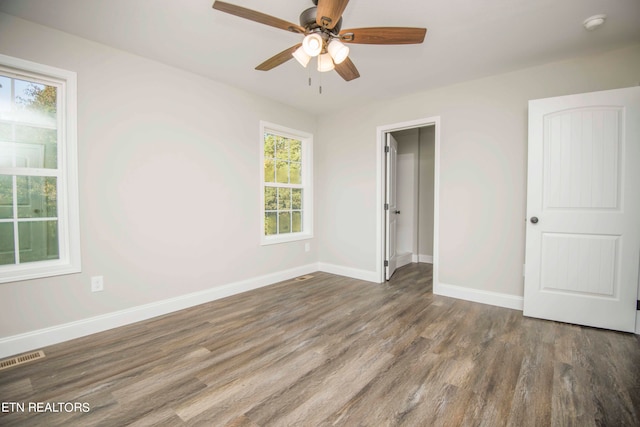 unfurnished bedroom with multiple windows, ceiling fan, and dark hardwood / wood-style flooring