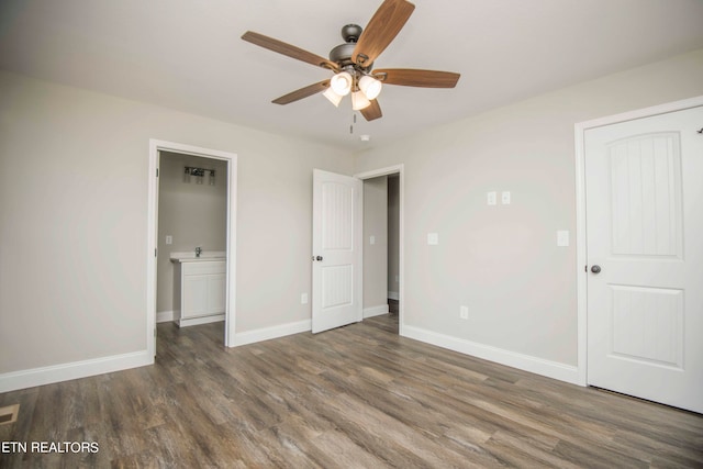 unfurnished bedroom featuring connected bathroom, dark hardwood / wood-style floors, ceiling fan, and a closet