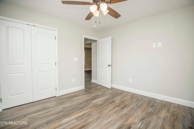 unfurnished bedroom with hardwood / wood-style flooring, ceiling fan, and a closet