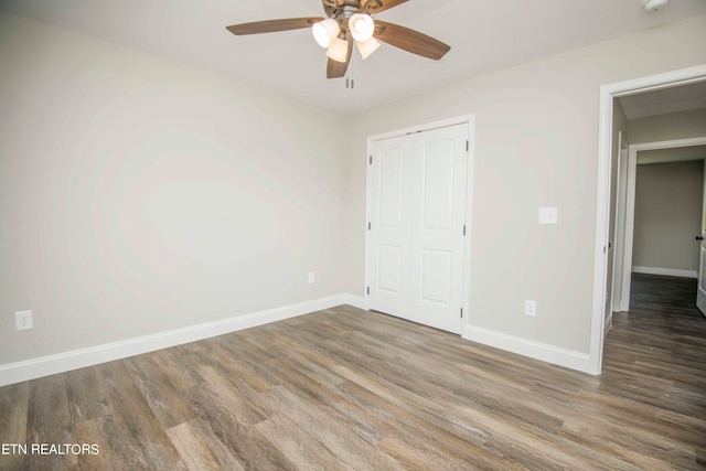 unfurnished bedroom with ceiling fan, dark wood-type flooring, and a closet