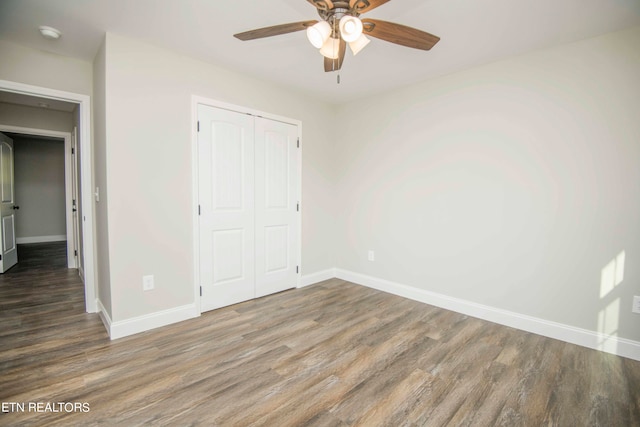 unfurnished bedroom featuring ceiling fan, a closet, and hardwood / wood-style floors