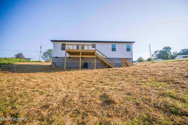 rear view of property featuring cooling unit and a wooden deck