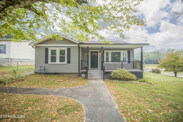 view of front of house with a front lawn, covered porch, fence, board and batten siding, and crawl space