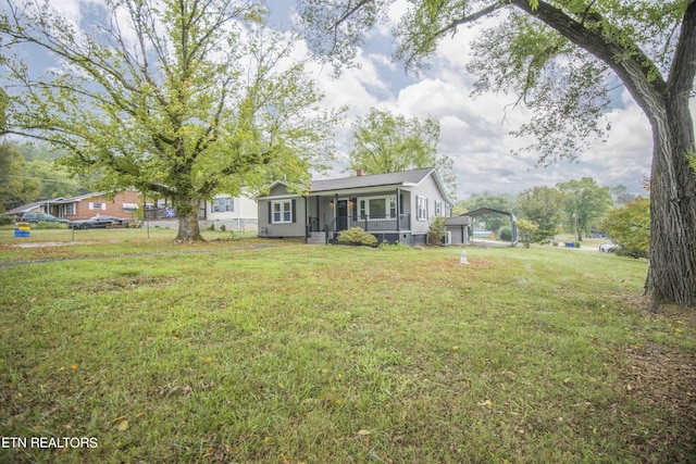 view of front of property with fence, a garage, covered porch, and a front yard