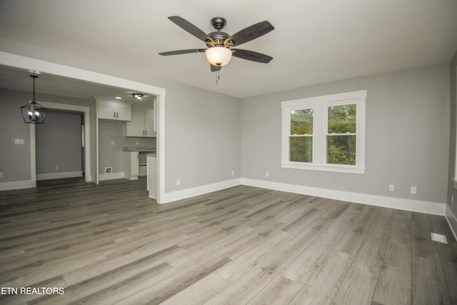 unfurnished living room with baseboards, a ceiling fan, and light wood finished floors