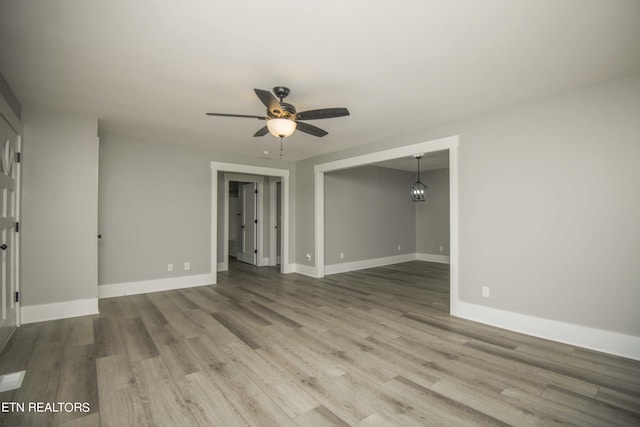empty room with ceiling fan, baseboards, and wood finished floors