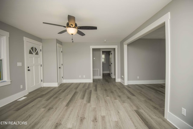 unfurnished living room with baseboards, a ceiling fan, visible vents, and light wood-style floors