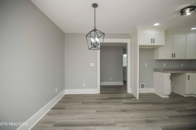kitchen featuring light wood finished floors, baseboards, a notable chandelier, and white cabinetry