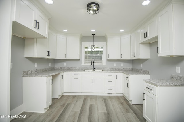 kitchen with white cabinetry, a sink, light wood-type flooring, and recessed lighting