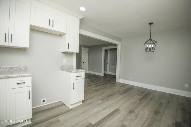kitchen featuring an inviting chandelier, light wood-style flooring, white cabinets, baseboards, and visible vents