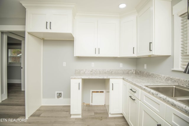 kitchen featuring light wood-style flooring, a sink, recessed lighting, white cabinetry, and light countertops