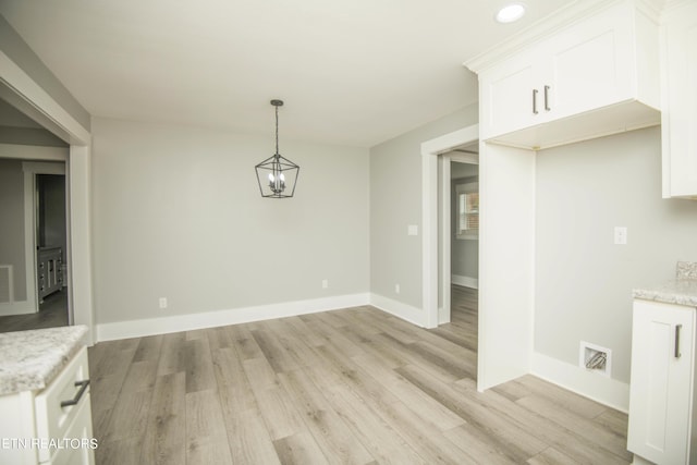 unfurnished dining area featuring visible vents, light wood finished floors, and baseboards