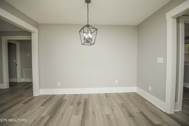 unfurnished dining area featuring baseboards, wood finished floors, and visible vents