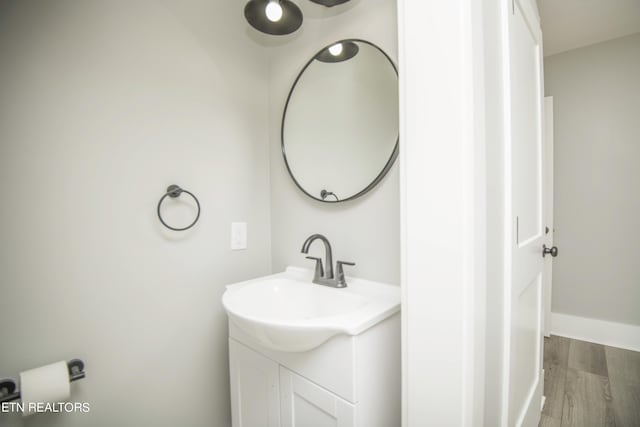 bathroom featuring baseboards, wood finished floors, and vanity
