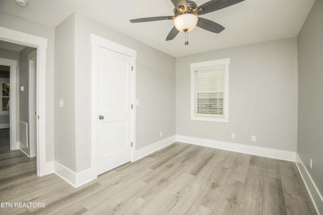 spare room with baseboards, a ceiling fan, visible vents, and light wood-style flooring