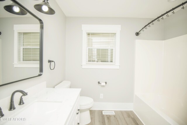 full bathroom with wood finished floors, vanity, bathtub / shower combination, baseboards, and toilet